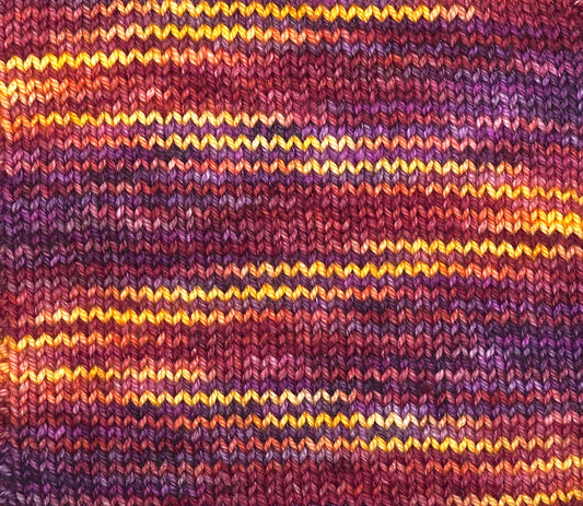 Close-up of a knitted fabric with multicolored stripes in purple, orange, and yellow.