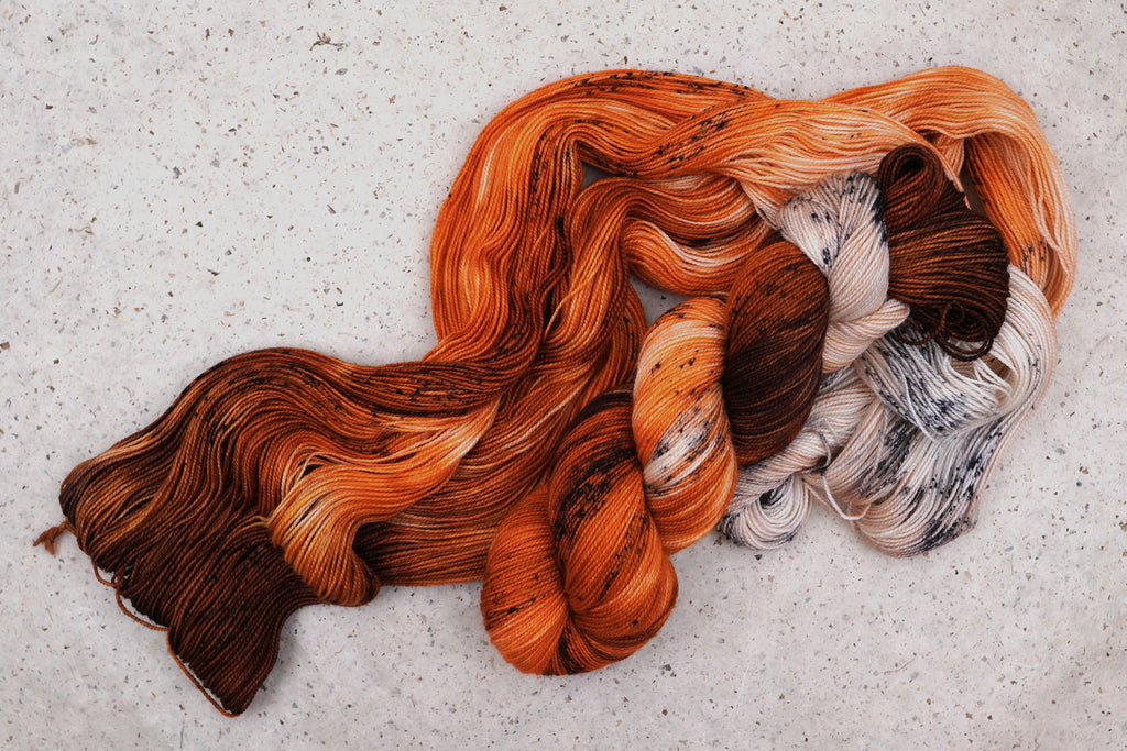 Wild Woollys Autumn Mocha yarn, an unwound skein showing brown, orange, and cream with dark speckles