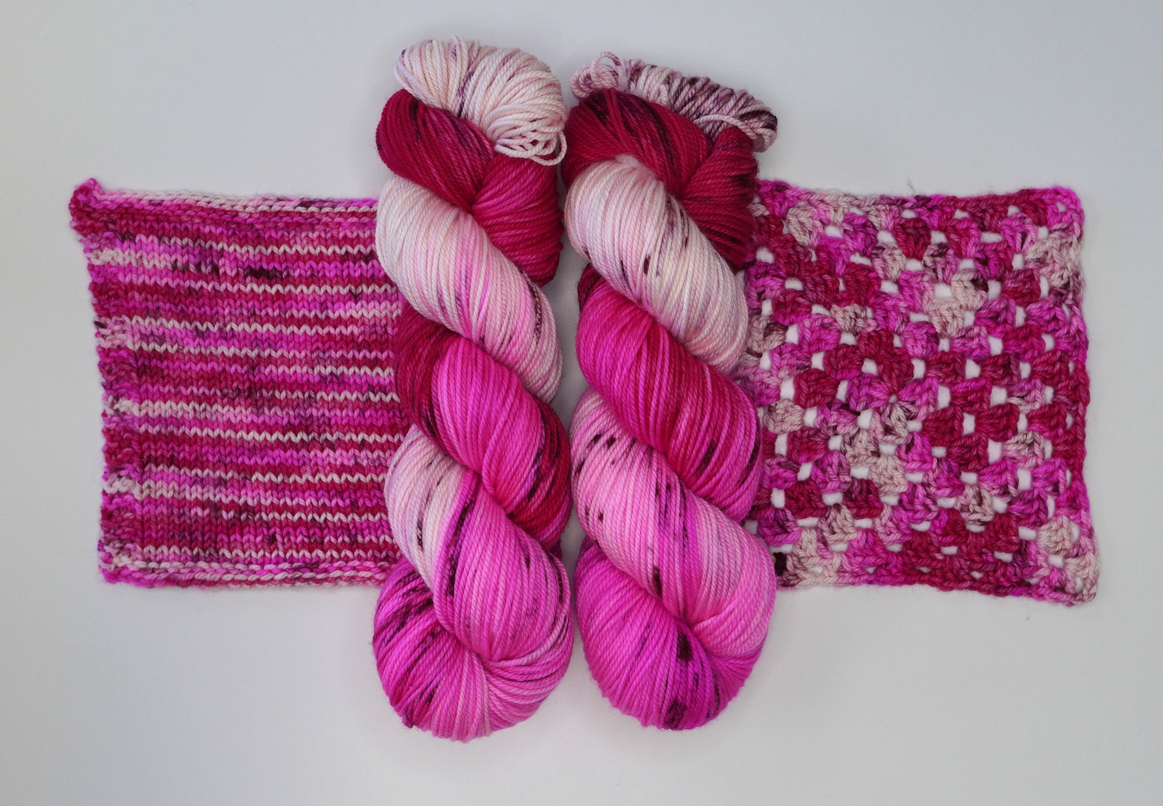 Two skeins of Wild Woollys Cherry Blossom yarn with knitted and crocheted swatches
