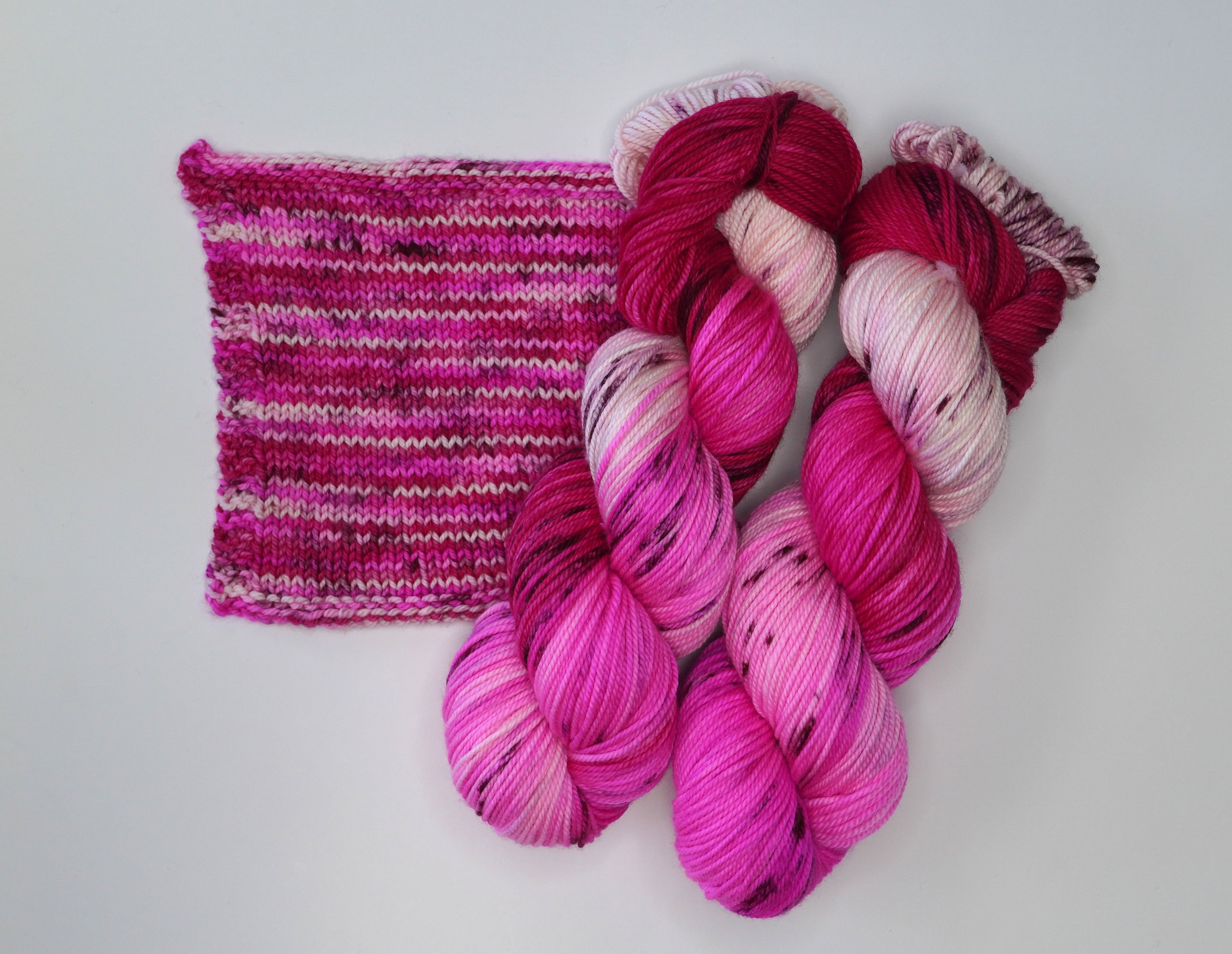 Wild Woollys Cherry Blossom yarn in skeins and a knitted swatch