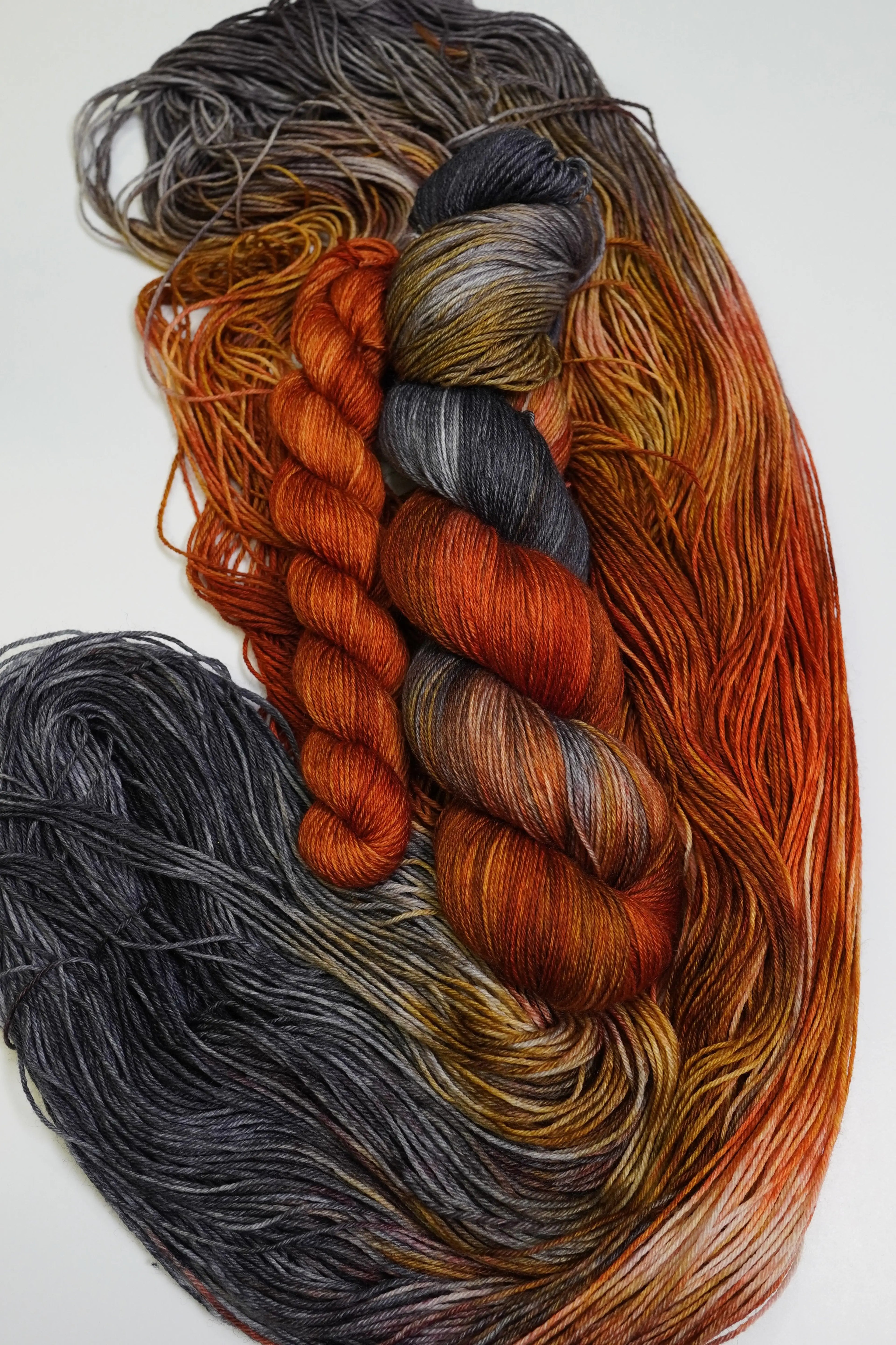 Wild Woollys Cobalt Rust Fingering Sock Set yarn in skeins and hanks, featuring rust, grey, and gold colors