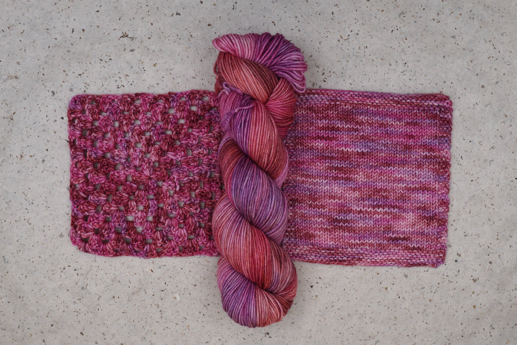 Wild Woollys Carnation Street yarn in pink and magenta, one skein with knitted and crocheted swatches