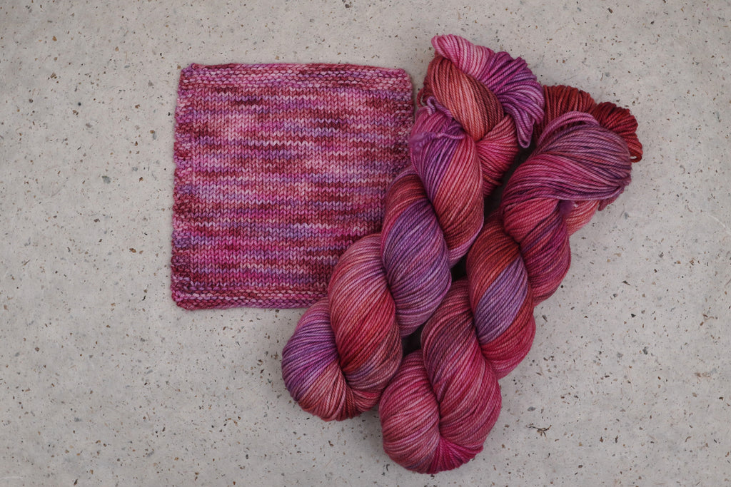 Wild Woollys Carnation Street yarn in pink and magenta, two skeins with a knitted swatch
