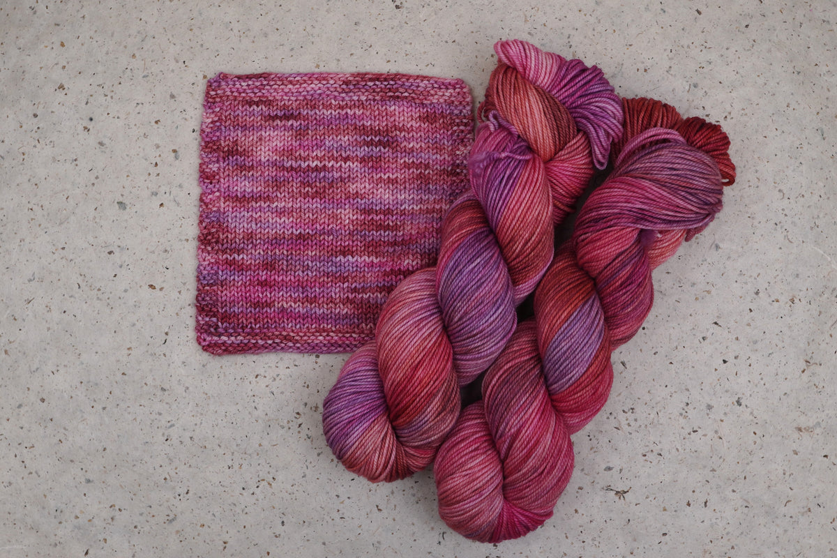Wild Woollys Carnation Street yarn in pink and magenta, two skeins with a knitted swatch
