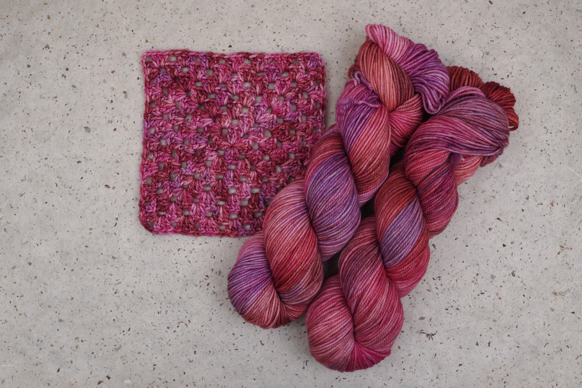 Wild Woollys Carnation Street yarn in pink and magenta, two skeins with a crocheted swatch