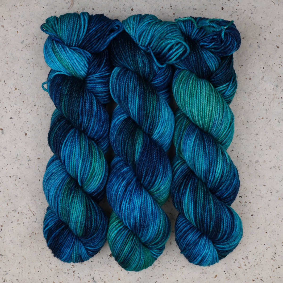 Hilo Cerulean Rhapsody DK de Wild Woollys — tres madejas en verde azulado, turquesa y azul intenso