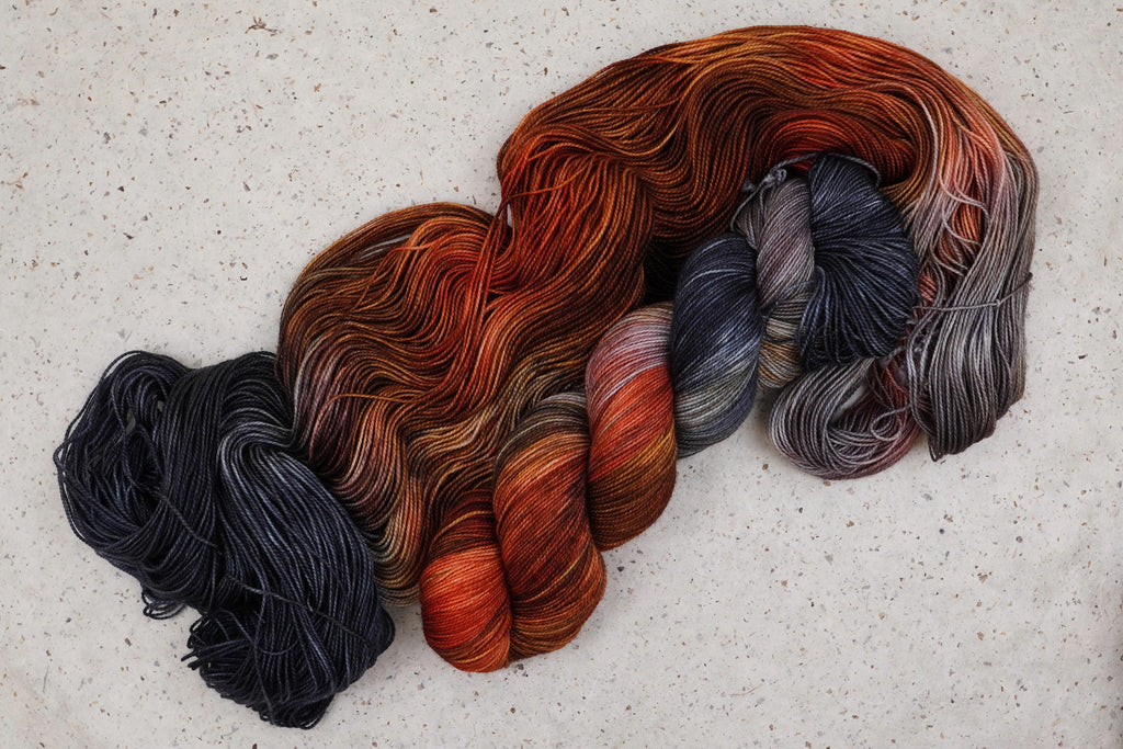 Wild Woollys Cobalt Rust Garn, gedrehte Stränge auf einem geöffneten Strang in Anthrazitgrau, Schieferblau und Rostorange