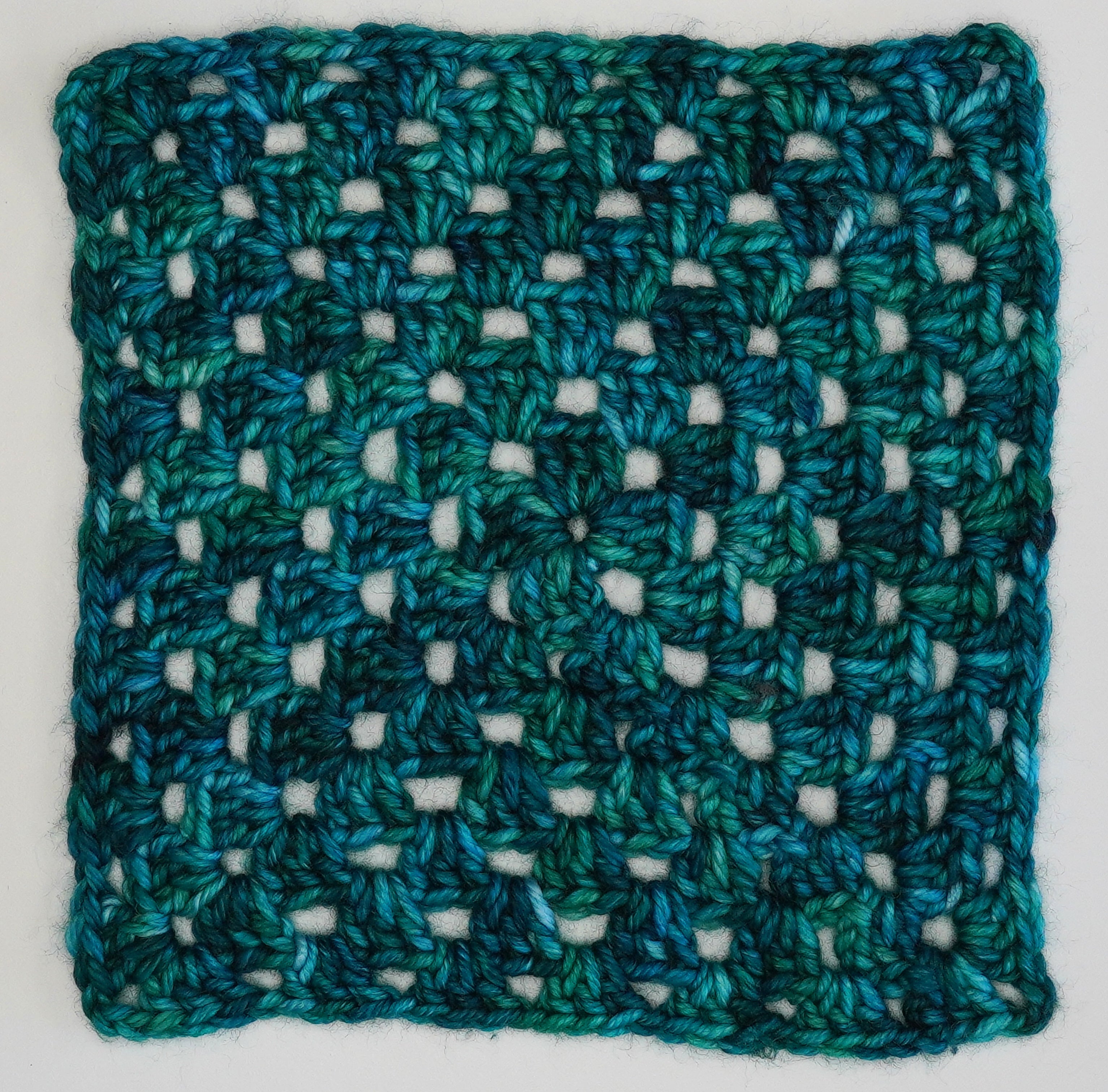 Cerulean Rhapsody Wild Woollys yarn, a crocheted square in shades of blue and green