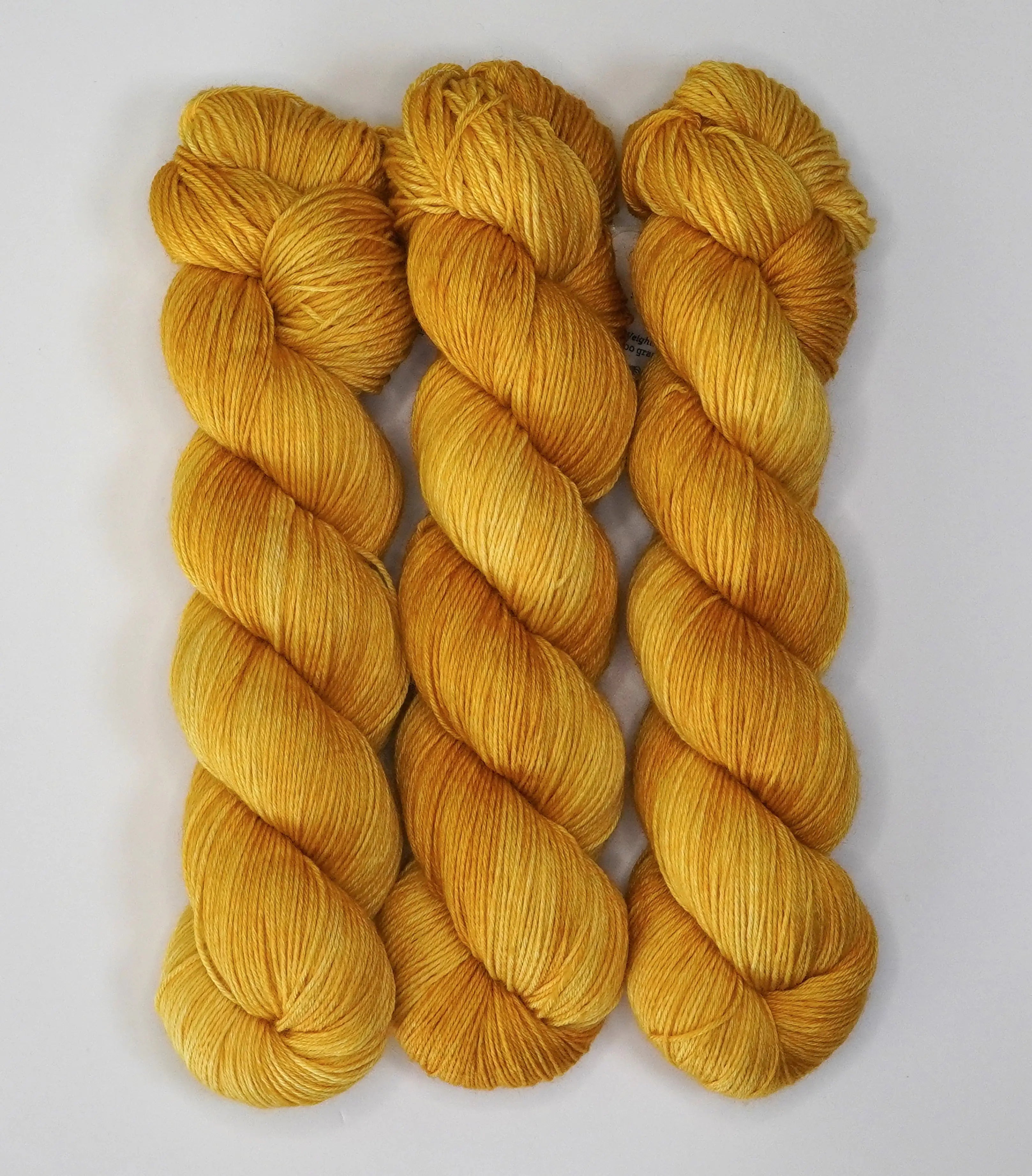 Three skeins of Wild Woollys Hayday yarn in a bright yellow color