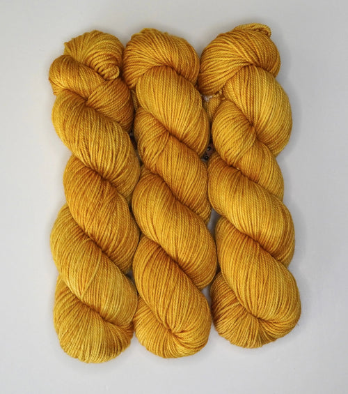 Wild Woollys Hayday yarn in three skeins, a bright golden yellow color