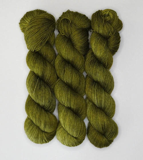 Three skeins of Wild Woollys Fiddlehead Fern yarn, a deep olive green color, on a white background