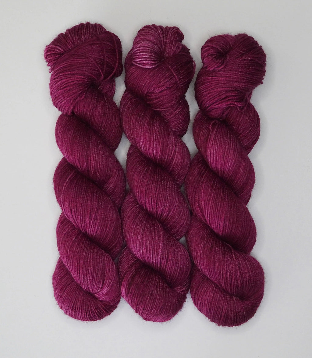 Three skeins of Wild Woollys Fuchsia Nostalgia yarn in a deep magenta color