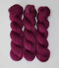 Three skeins of Wild Woollys Fuchsia Nostalgia yarn in a deep fuchsia color