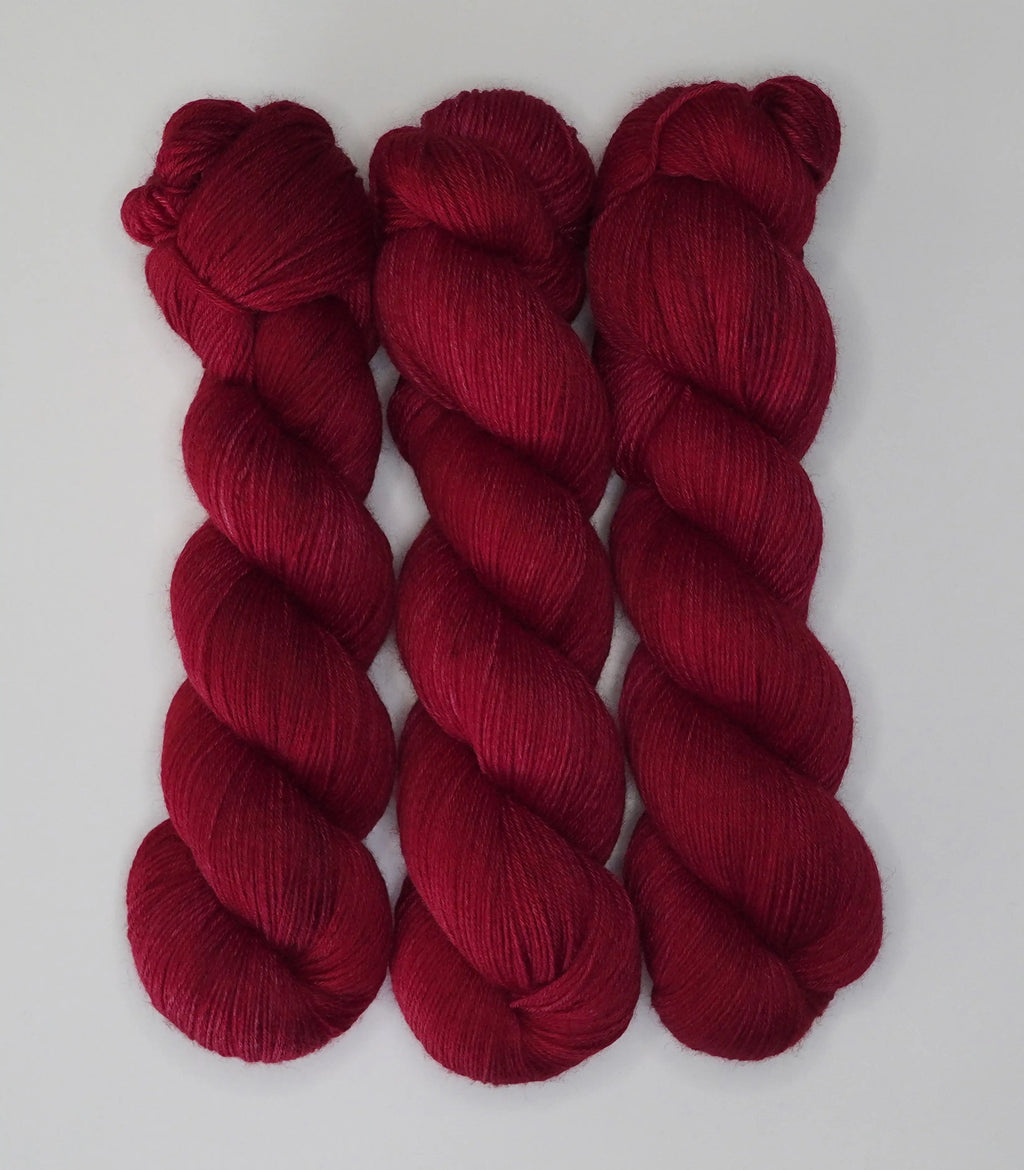 Three skeins of Wild Woollys Divine Wine yarn in a rich red color
