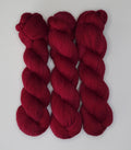 Three skeins of Wild Woollys Divine Wine yarn in a rich red color