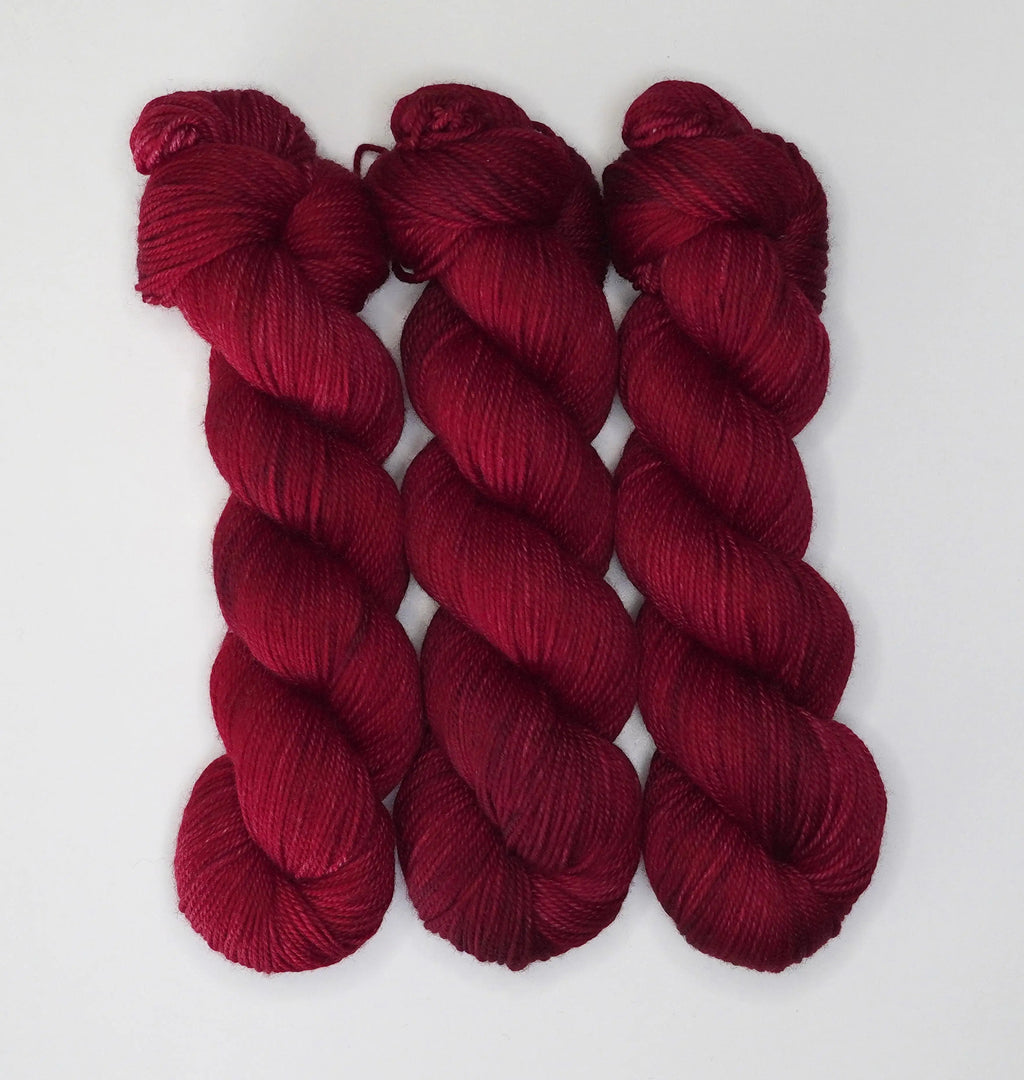 Three skeins of Wild Woollys Divine Wine yarn in a deep red color