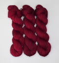Three skeins of Wild Woollys Divine Wine yarn in a deep red color
