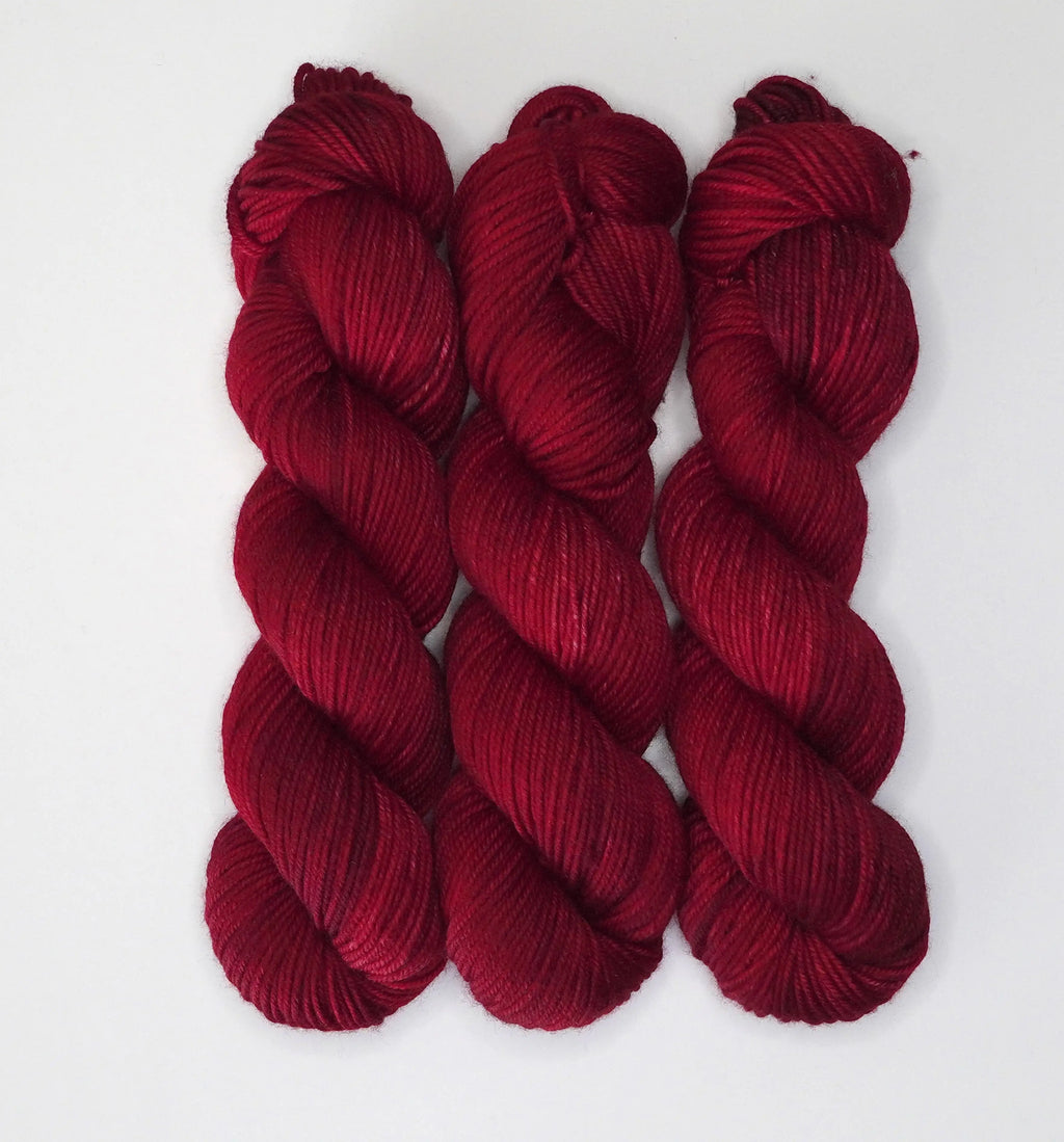 Three skeins of Wild Woollys Divine Wine yarn in a rich red hue
