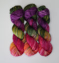 Wild Woollys Summer Berry yarn in three skeins, transitioning from purple and green to pink and orange