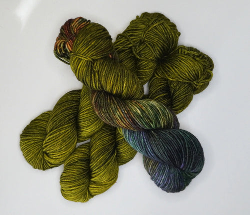 Wild Woollys Fiddlehead Fern yarn, a skein of green and variegated dark green, purple, and brown yarn