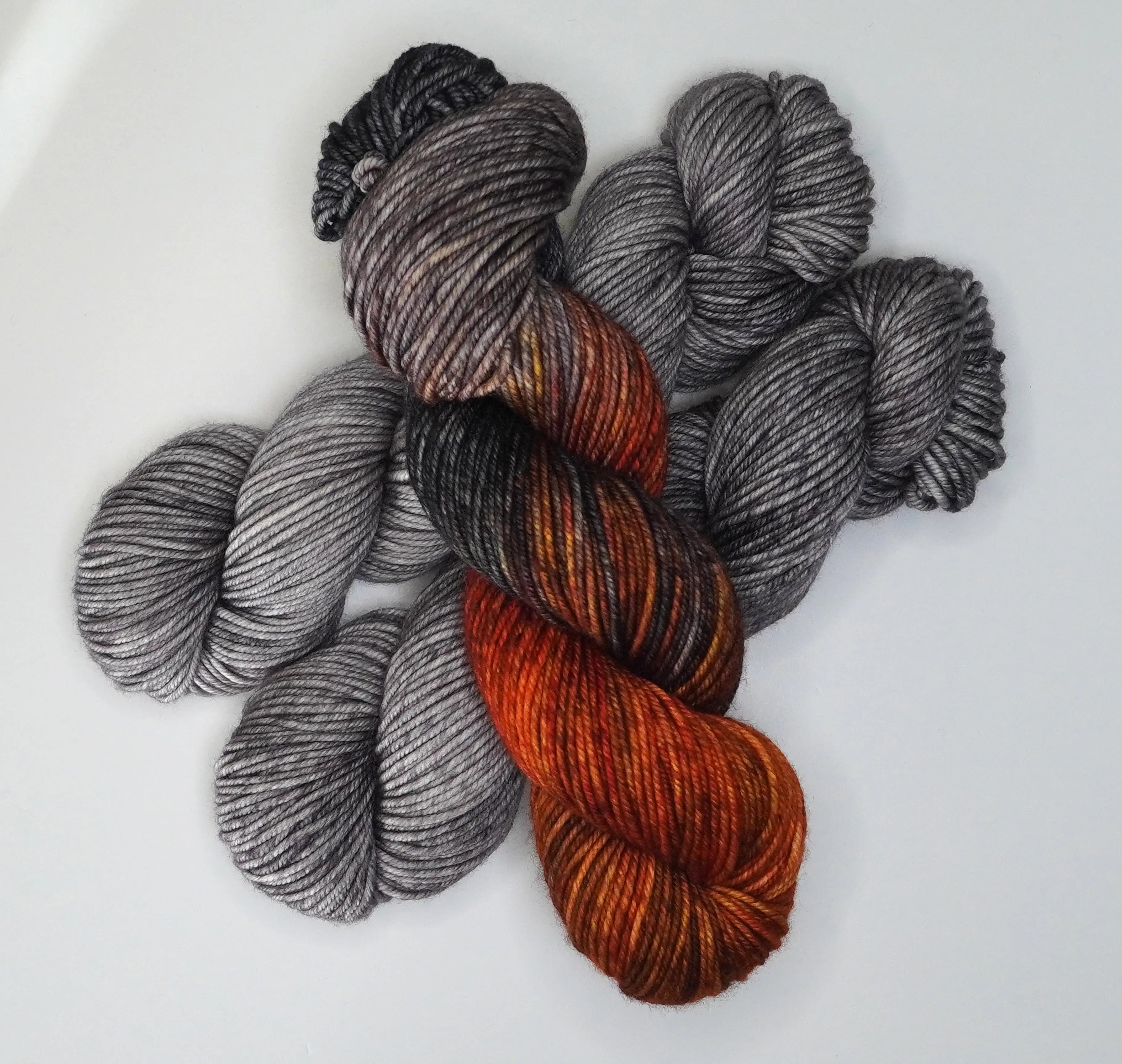 Wild Woollys Grey Expectations yarn in skeins of grey and variegated orange