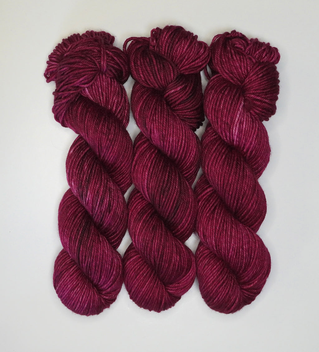 Three skeins of Wild Woollys Fuchsia Nostalgia yarn in a deep fuchsia color