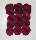 Three skeins of Wild Woollys Fuchsia Nostalgia yarn in a deep fuchsia color