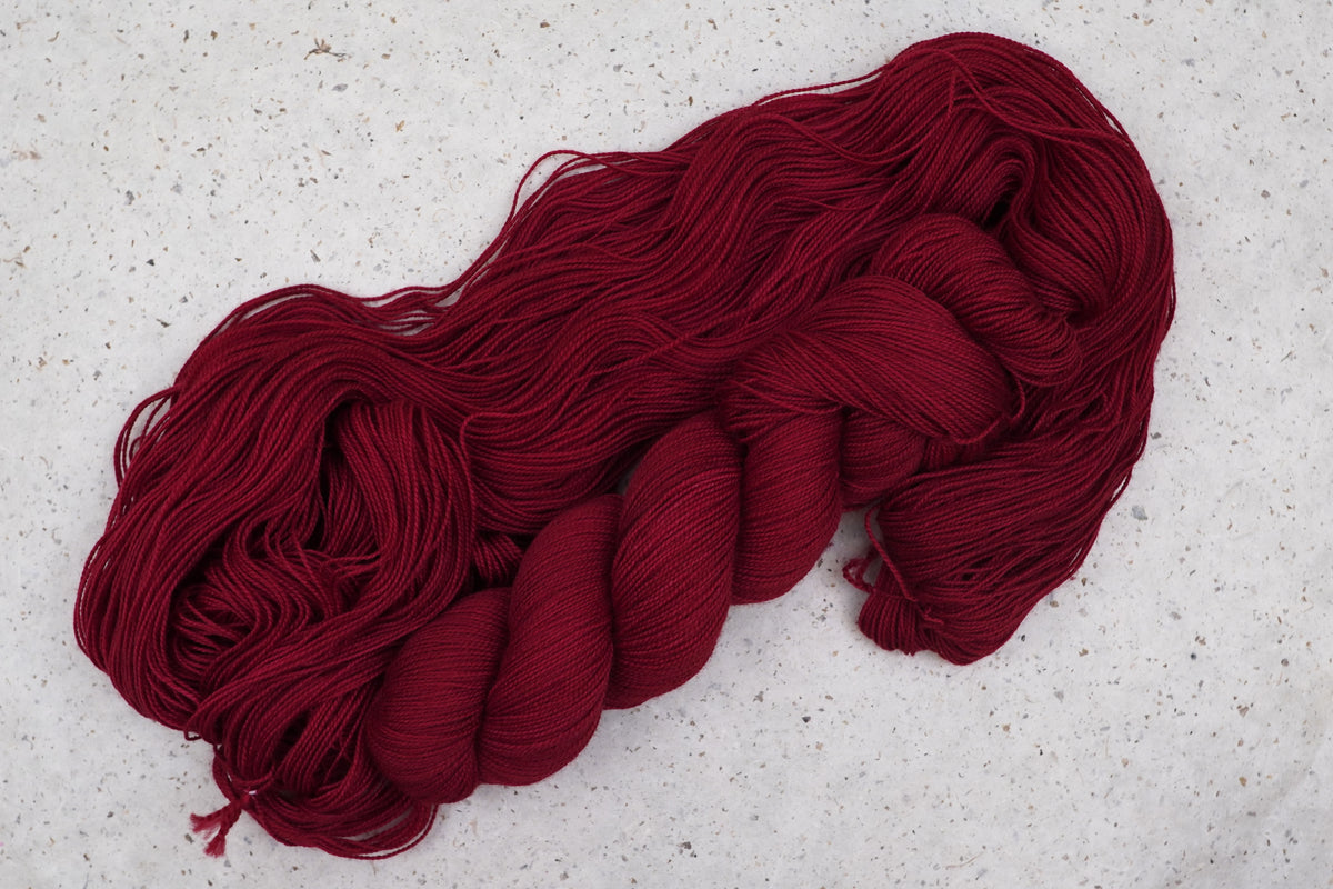 Wild Woollys Divine Wine yarn, an unwound skein showing deep burgundy red