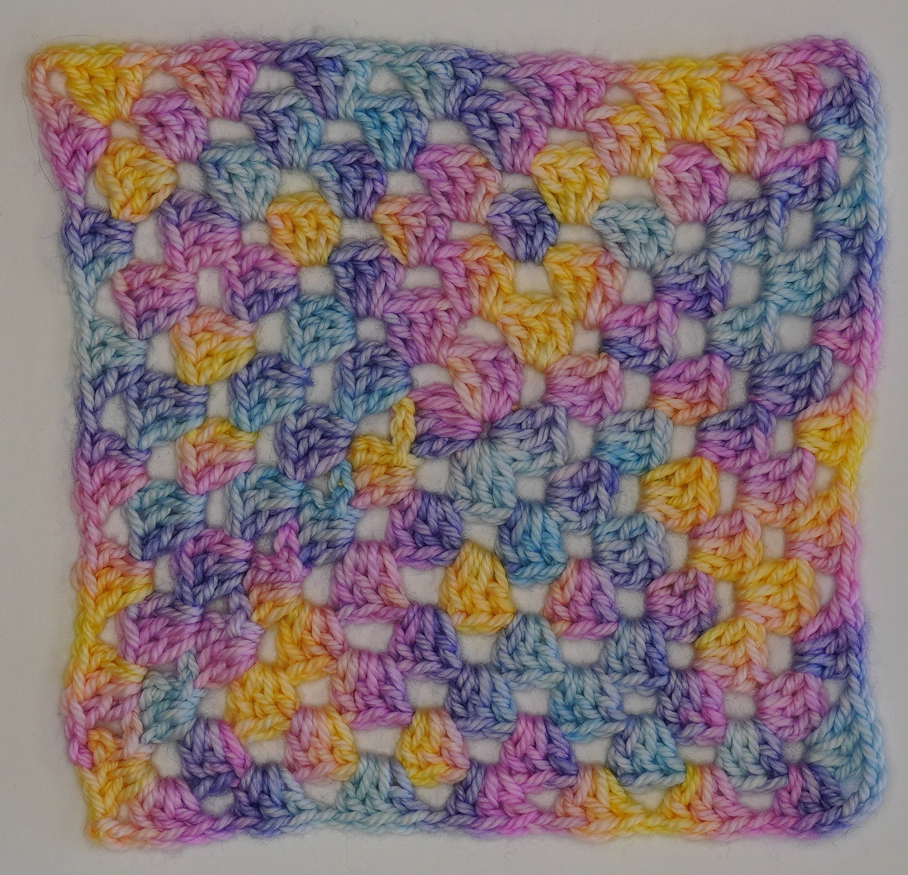 Wild Woollys Fantasy yarn swatch, crocheted in a granny square pattern with pastel yellow, pink, blue, and purple
