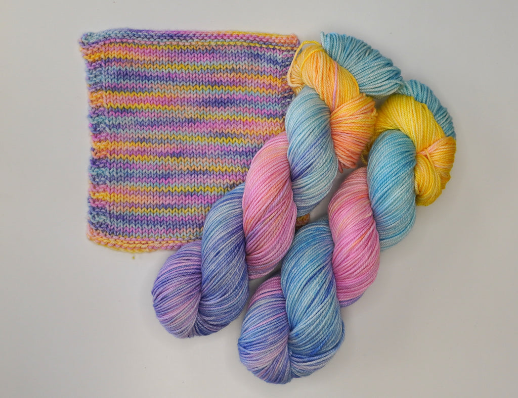 Wild Woollys Fantasy yarn in pastel pink, blue, purple, yellow, and orange with a knitted swatch