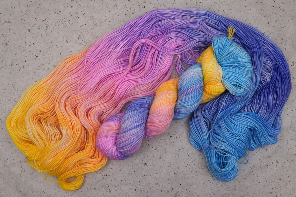 Hilo Fantasy de Wild Woollys — una madeja abierta en azul cielo, amarillo, melocotón, rosa y azul violáceo