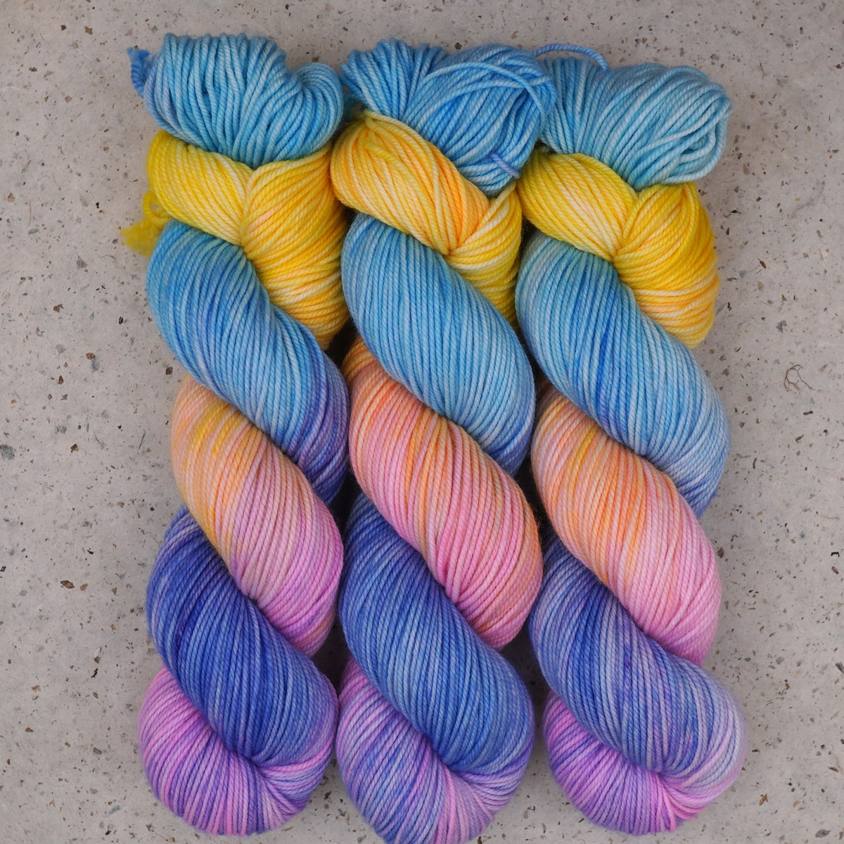 Hilo Fantasy DK de Wild Woollys — tres madejas en azul cielo, amarillo, melocotón, rosa y azul violáceo