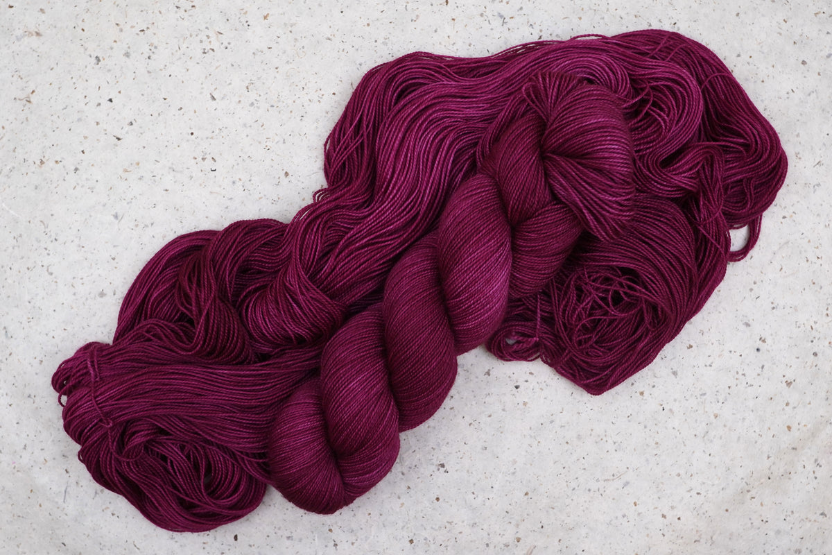 Wild Woollys Fuchsia Nostalgia yarn, an unwound skein showing deep magenta and berry pink