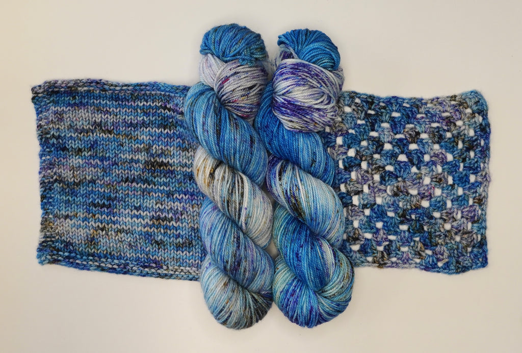 Wild Woollys Galaxy Voyage yarn in two skeins and two knitted swatches, blue, purple, and white