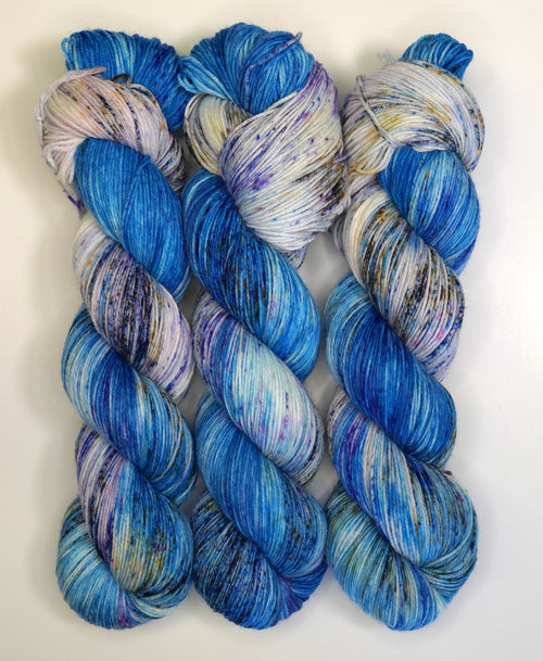 Three skeins of blue and purple yarn on a white background