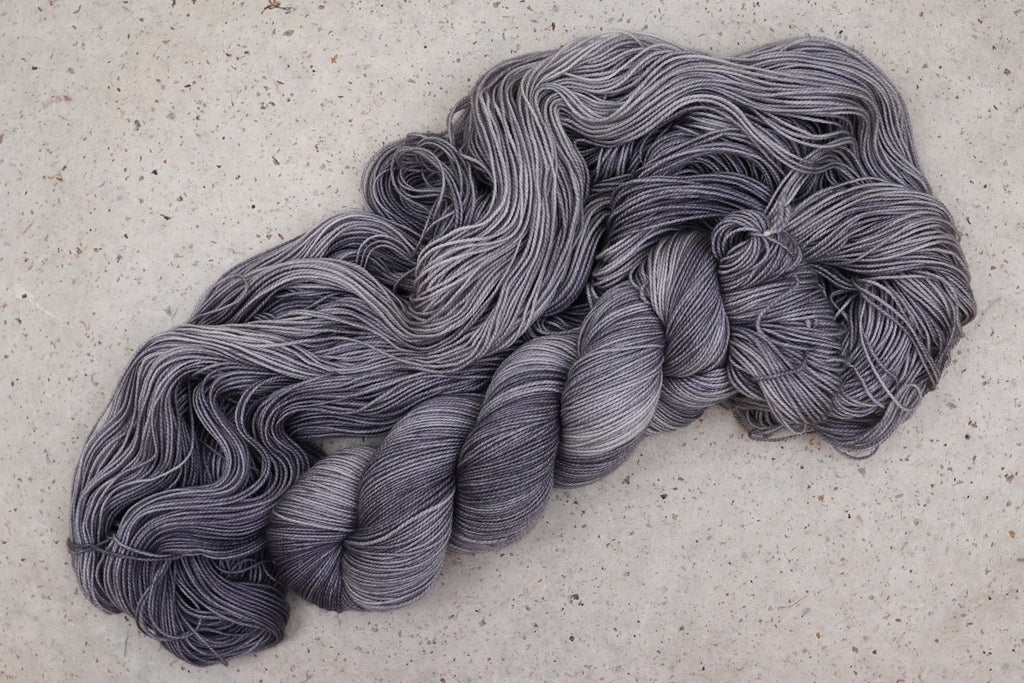 Hilo Grey Expectations de Wild Woollys — una madeja abierta en gris suave y plata