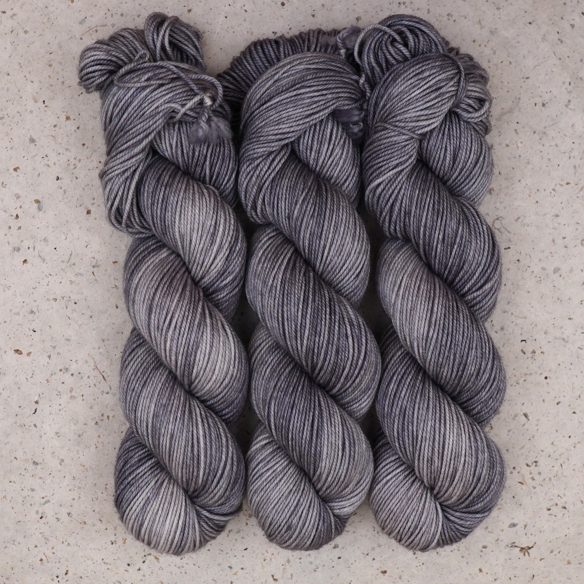 Wild Woollys Grey Expectations DK yarn, three skeins in soft grey and silver