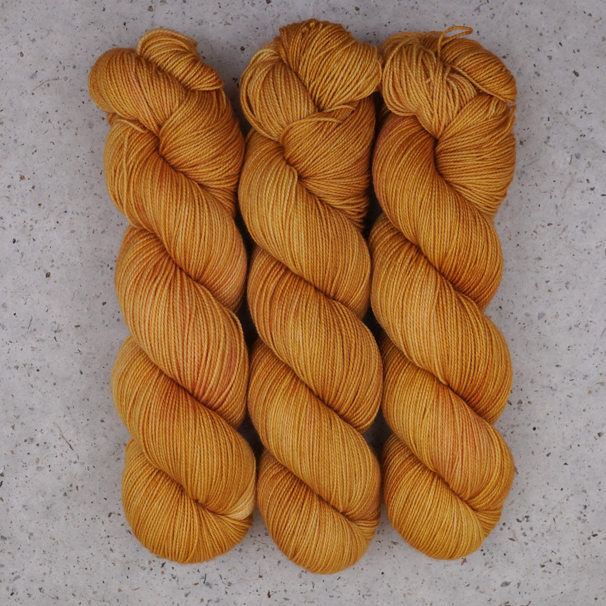 Wild Woollys Hayday Fingering yarn, three skeins in golden yellow and warm amber