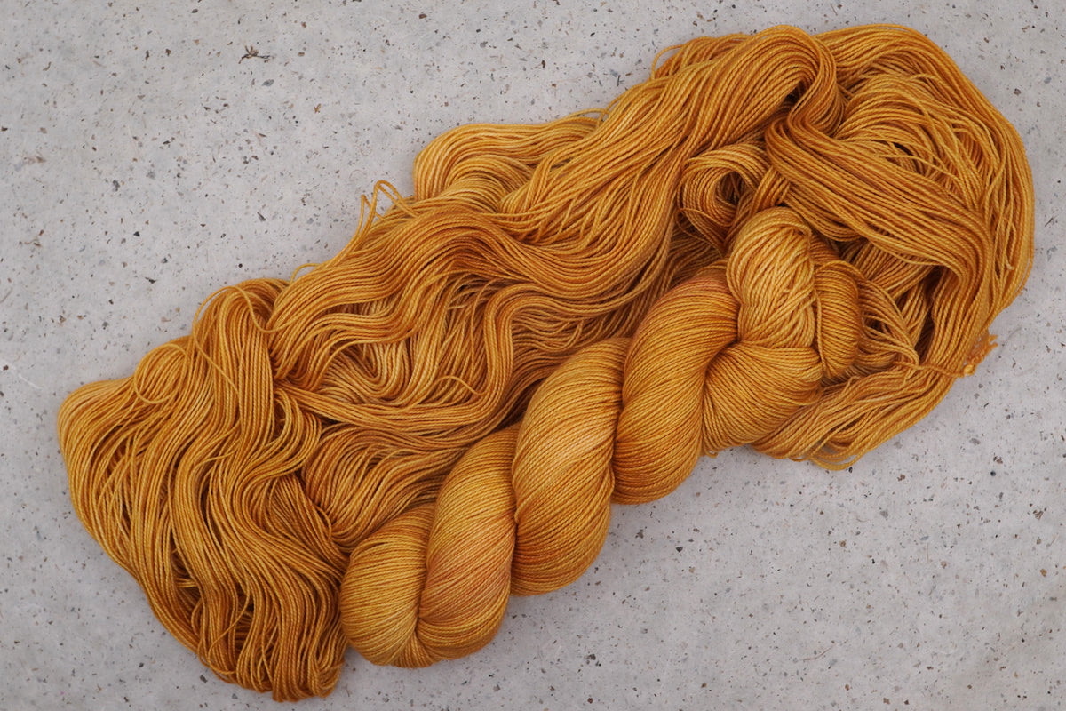 Wild Woollys Hayday yarn, an unwound skein showing golden yellow and warm amber