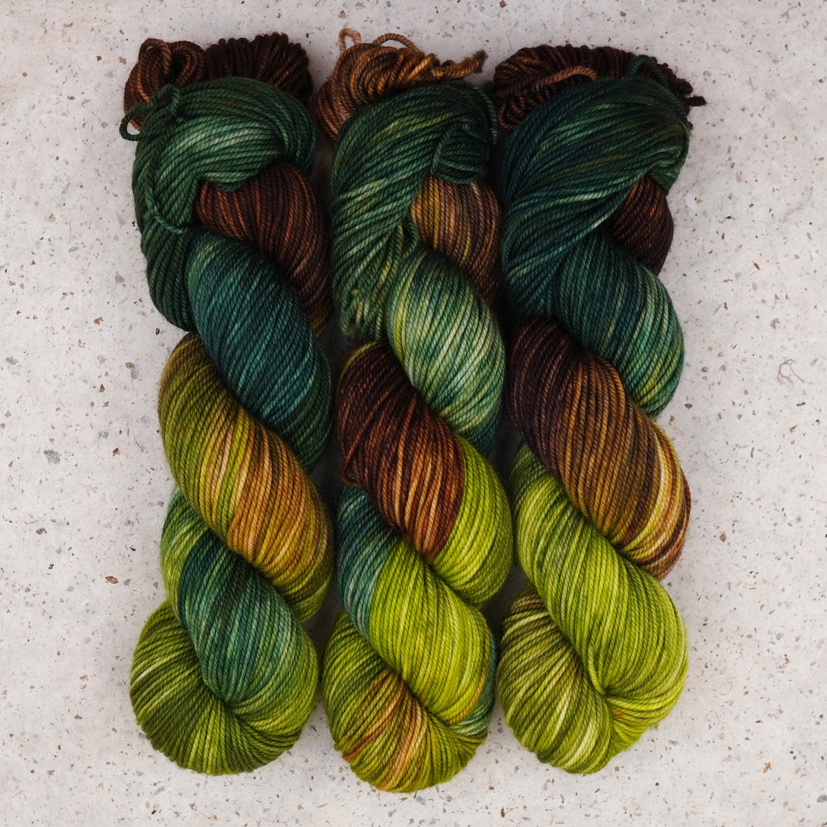 Hilo Jungle Juice DK de Wild Woollys — tres madejas en verde oscuro, lima y marrón cálido