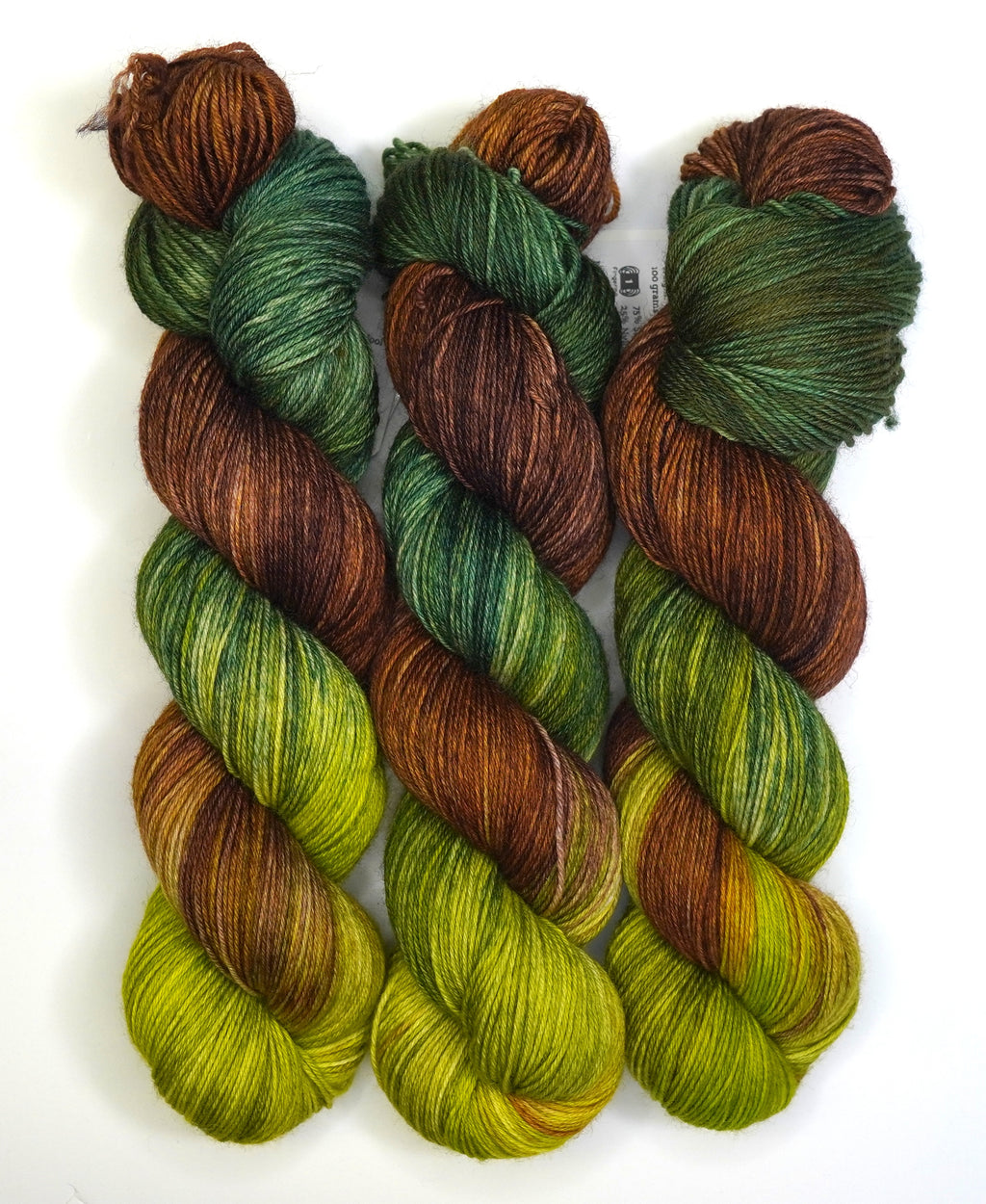 Three skeins of green and brown yarn on a white background
