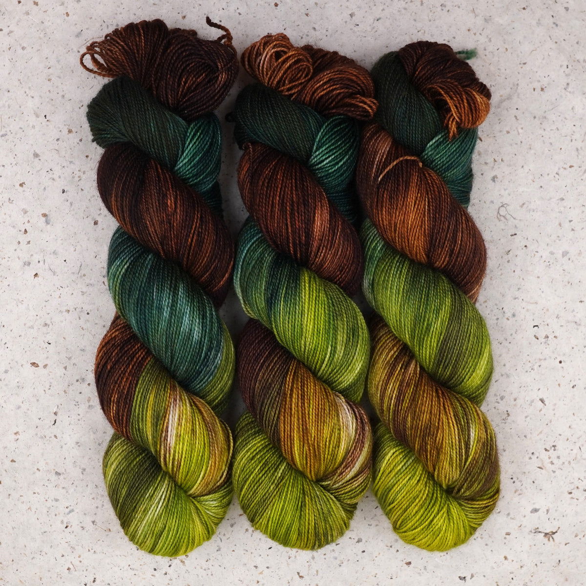Hilo Jungle Juice Fingering de Wild Woollys — tres madejas en verde oscuro, lima y marrón cálido