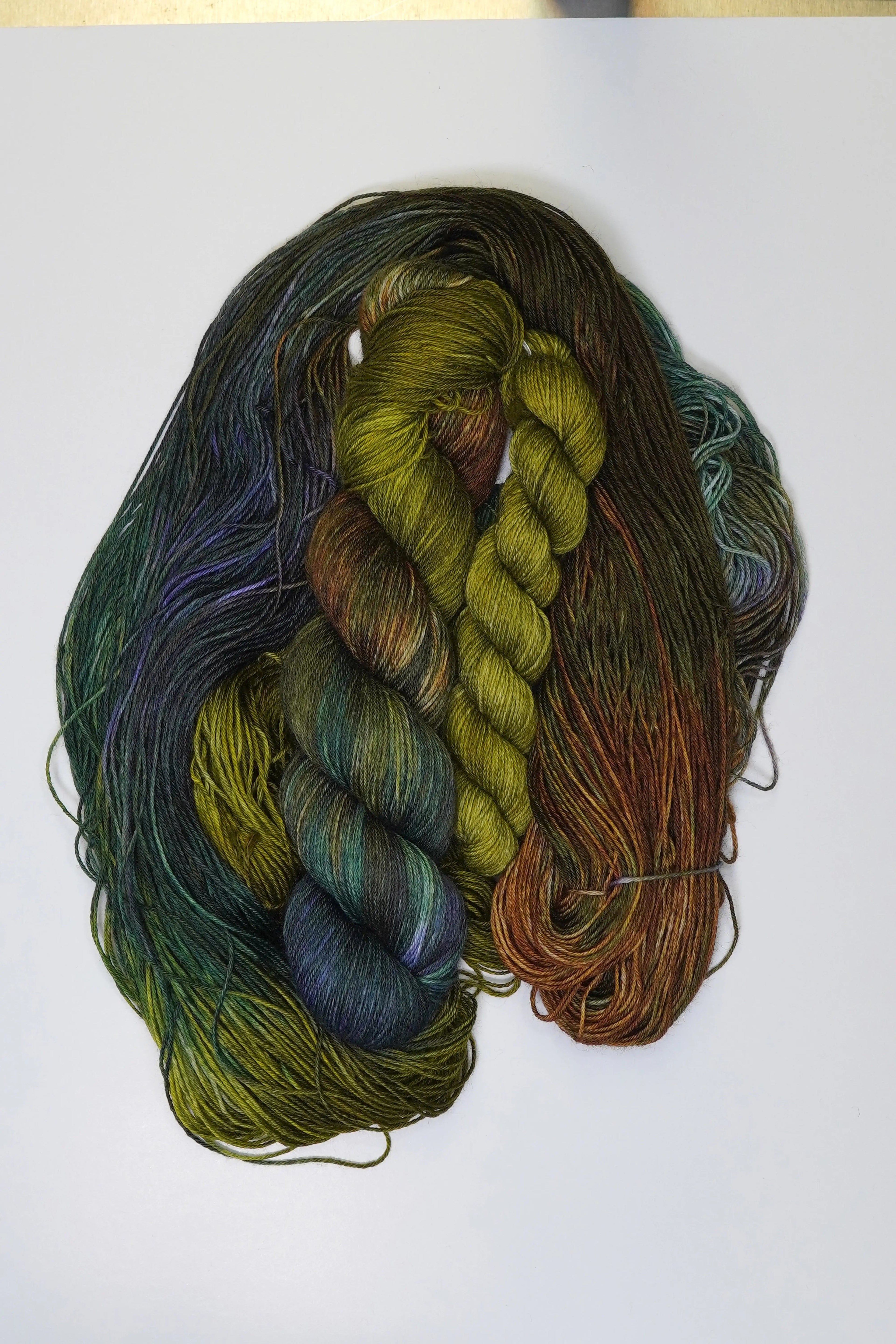 Wild Woollys Mycelium Bloom Fingering Sock Set yarn in shades of green, brown, and purple