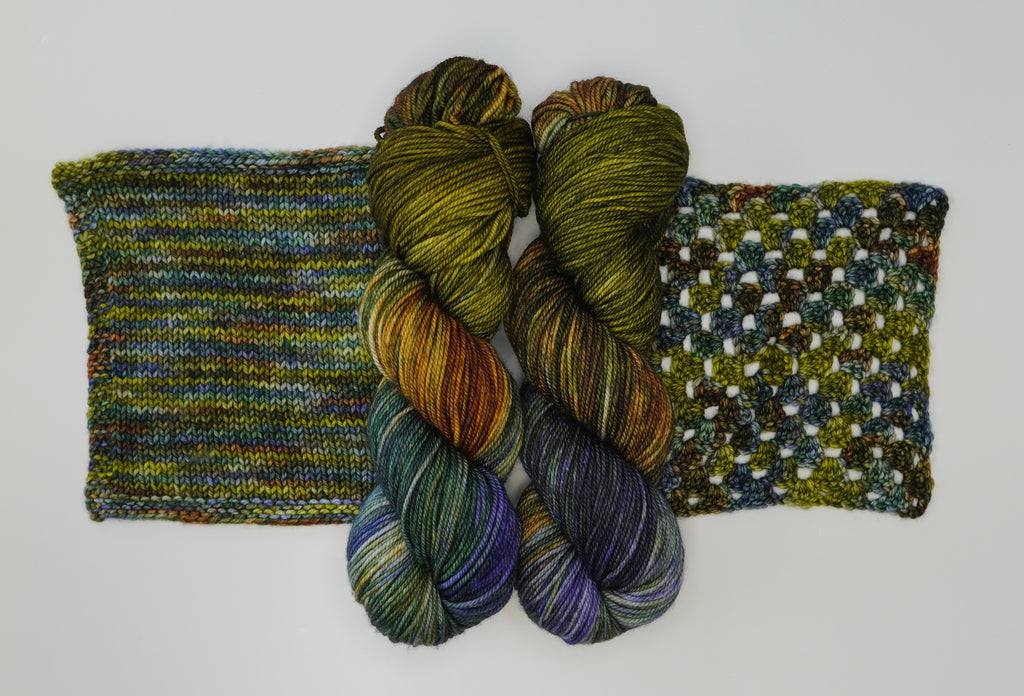 Two skeins of variegated yarn in green, blue, purple, and brown, with knitted and crocheted swatches