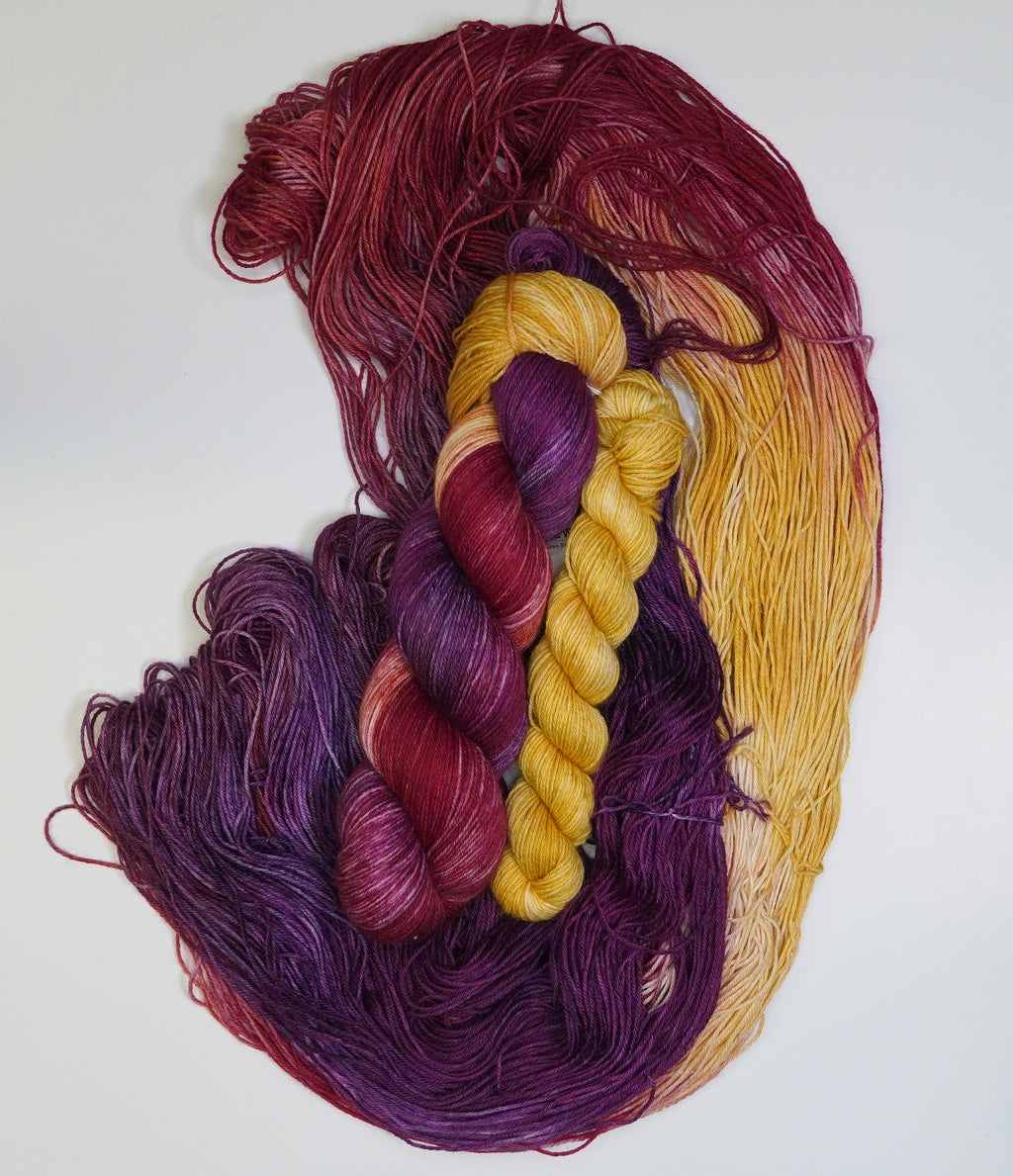 Braided skeins of purple and yellow yarn on a white background