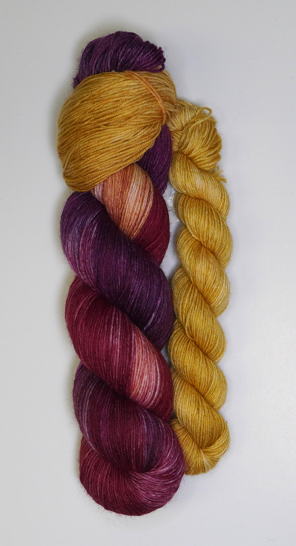 Two skeins of yarn, one purple and one yellow, on a white background.