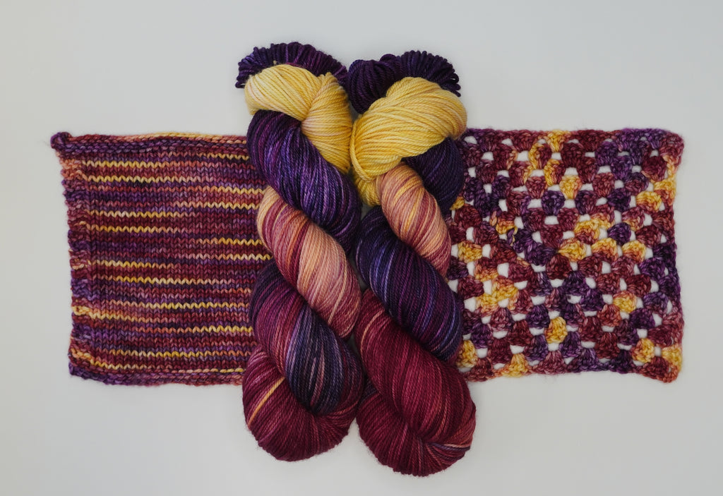 Maizie Dayz yarn by Wild Woollys, two skeins and two swatches, in shades of yellow, purple, and red