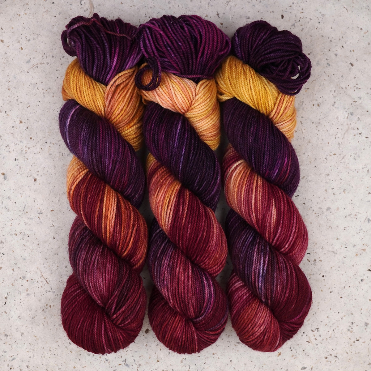 Hilo Maizie Dayz DK de Wild Woollys — tres madejas en morado intenso, dorado, magenta y carmesí