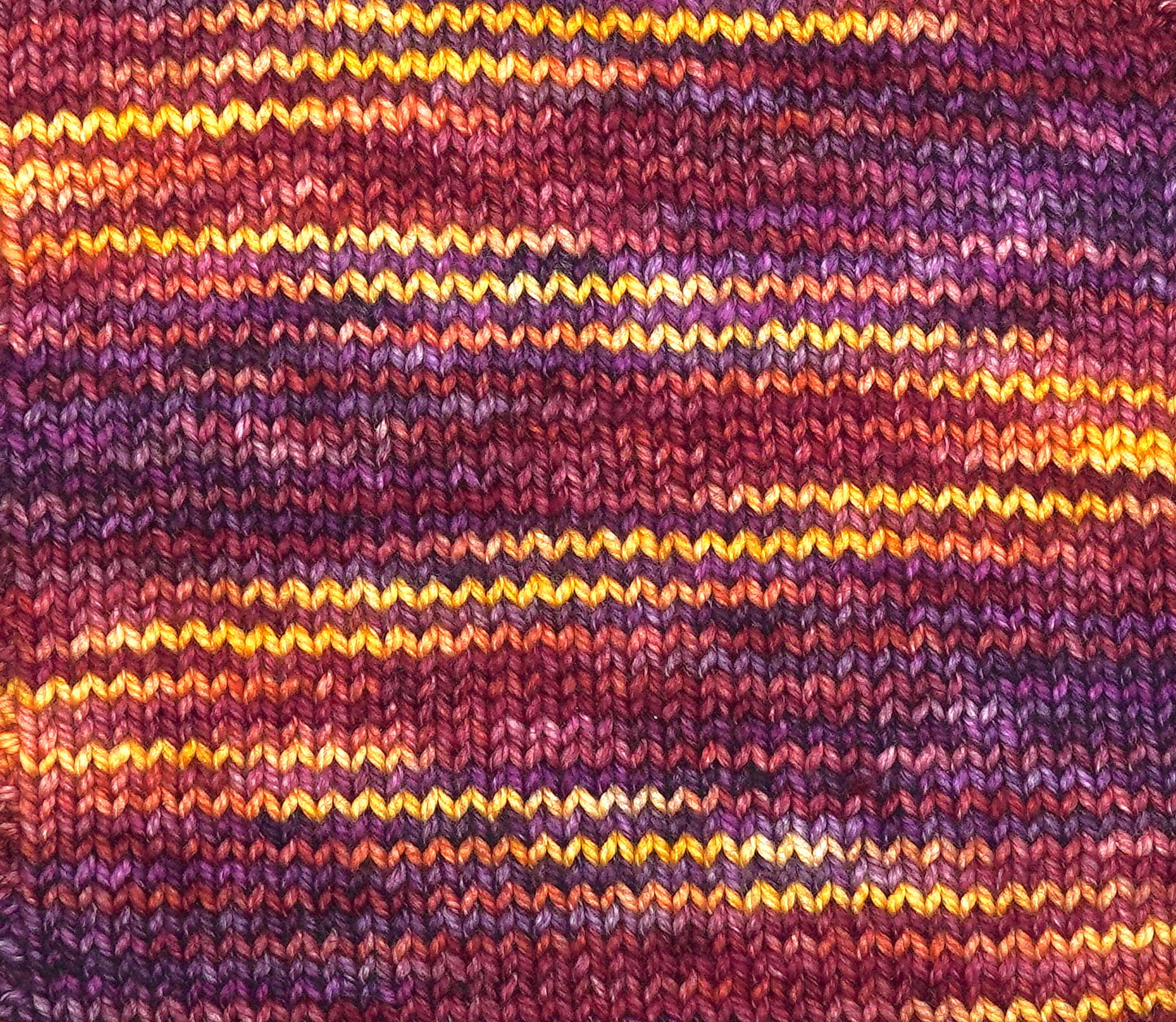 Close-up of a knitted fabric with multicolored stripes in purple, orange, and yellow.