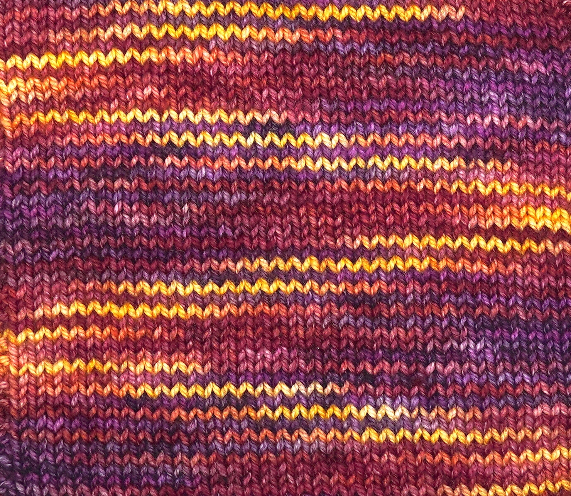 Close-up of a knitted fabric with multicolored stripes in purple, orange, and yellow.